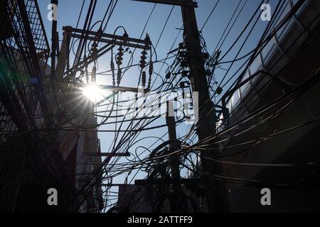 Silhouette di cavi elettrici disordinati con il sole Foto Stock