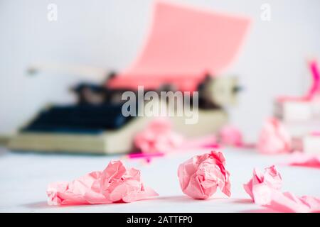 Palline di carta sbriciolate e una macchina da scrivere su un luogo di lavoro scrittore. Intestazione creativa femminile. Foto Stock