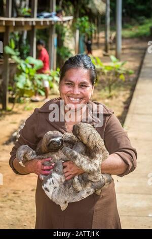 Donna con il suo 'animale domestico' bruna-throtated slaths, Bradypus variegatus, San Francisco Village, Loreto, Perù, Sud America Foto Stock