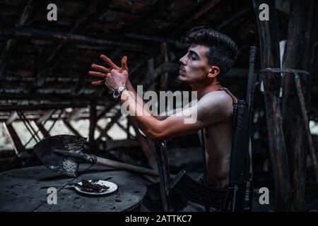 Il giovane membro rivoluzionario o membro della banda mafia sta facendo un lavoro sporco. Si trova nella mansarda. Mafia Concetto. Foto Stock