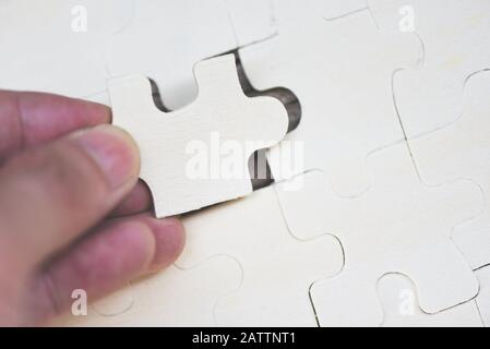 Uomo d'affari che tiene il puzzle / primo piano di pezzi di puzzle per unire e provare a collegare il concetto di partnership di affari Foto Stock