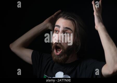 Giovane appassionato di calcio hipster, stordita gioire, sfondo isolato nero. Concetto di tifosi di calcio. Foto Stock