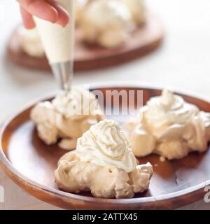 , decorando la meringa con crema dalla borsa culinaria Foto Stock