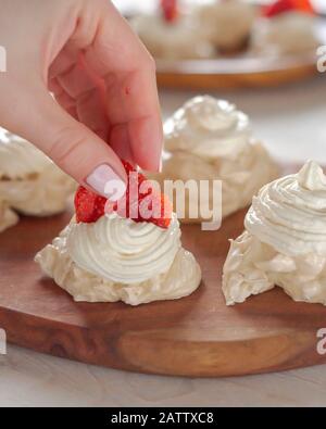 Il processo di creazione di Pavlova dessert, decorazione della meringa con fragole Foto Stock