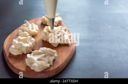 Il processo di creazione di Pavlova dessert, decorazione della meringa con crema Foto Stock