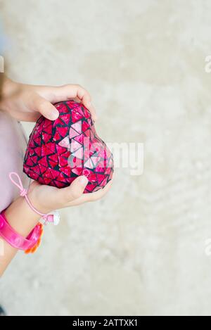 cuore rosso nelle mani di un bambino. vista dall'alto Foto Stock