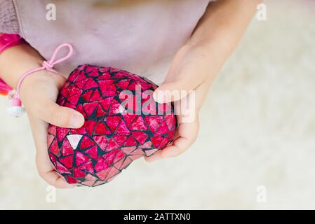 cuore rosso nelle mani di un bambino. vista dall'alto Foto Stock