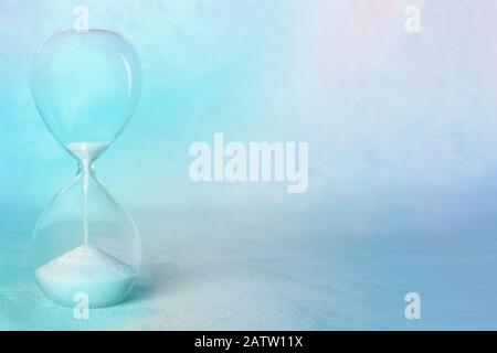Concetto di tempo. Una clessidra con il periodo che arriva alla fine, con spazio di copia, in blu teale, immagine tonata Foto Stock