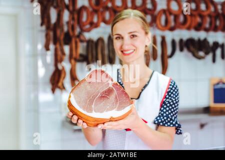 Venditore che tiene il prosciutto nella sua mano in macelleria, fuoco sulla carne Foto Stock