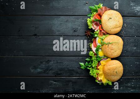 Set di hamburger con carne, formaggio, pesce e verdure. Su sfondo nero. Vista dall'alto. Spazio libero per il testo. Foto Stock
