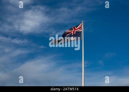 Sventolando la bandiera nazionale australiana contro il cielo blu sullo sfondo. Foto Stock