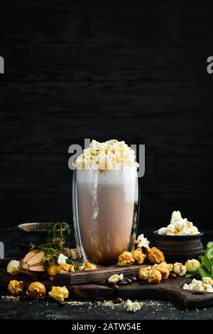 Cacao con latte e popcorn. Nel vetro. Vista dall'alto. Su sfondo nero. Foto Stock
