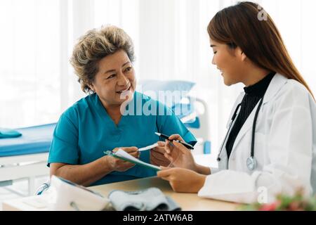 Terapia Smart Asian femminile in uniforme prescrizione scritta per i medicinali per pazienti di sesso femminile anziani in ospedale Foto Stock