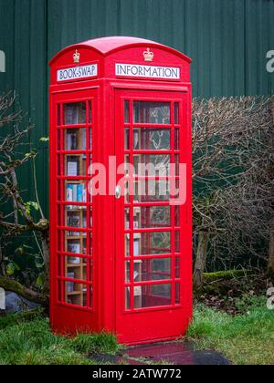 Una vecchia cabina telefonica rossa di tipo K6 che è stata convertita in un piccolo negozio e centro informazioni. Questa scatola si trova su una strada collinare nella scottis Foto Stock