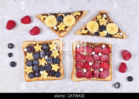 Cibo sano con fette di pane tostato farro condito con frutta come lampone rosso, mirtillo, banana e cereali di quinoa soffiato Foto Stock