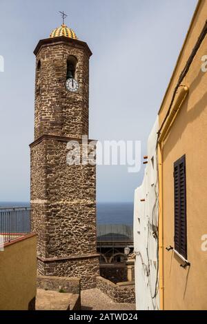 Cupola colorata in una torre di una chiesa di Sant'Antonio a Castelsardo, Sardegna, Italia. Orizzonte del mare mediterraneo e cielo blu sullo sfondo. Foto Stock