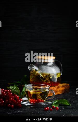 Tè da viburnum e erbe forestali. Bevande calde invernali. Su sfondo nero. Vista dall'alto. Foto Stock