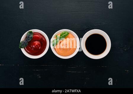 Tre salse in piattini. Ketchup, salsa di soia, salsa di paprika. Vista dall'alto. Spazio libero per il testo. Foto Stock