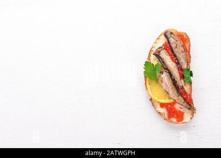 Panino con spratti, caviale, cipolla, su fondo di legno. Vista dall'alto. Spazio di copia. Foto Stock