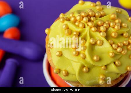 Compleanno cupcake in polka divertente punto tazze colorate stack e deflated palloncini su sfondo viola, primo piano, copia spazio Foto Stock