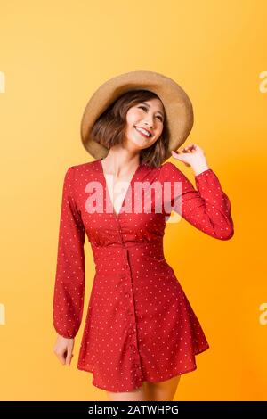 Ragazza asiatica indossando abito rosso con cappello di paglia su sfondo arancione Foto Stock