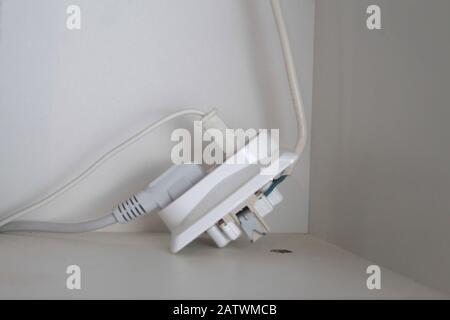 Due spine elettriche sono collegate a una presa rotta. Foto Stock