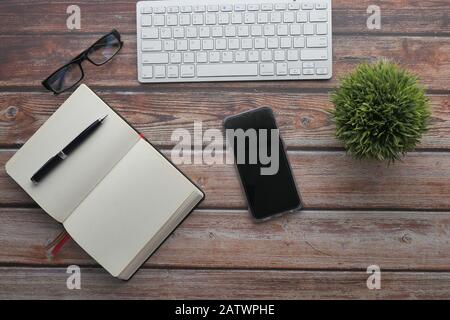 vista dall'alto dello smartphone , della tastiera e dell'agenda aperta sul tavolo Foto Stock