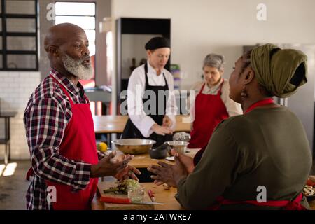 Gli chef discutono mentre cucinano Foto Stock