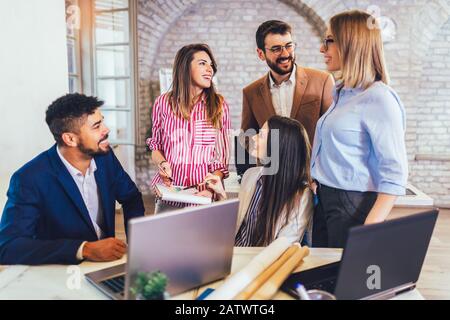 Un giovane team di colleghi che si occupa di una grande discussione durante un moderno ufficio di lavoro. Foto Stock