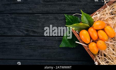 Kumquat. Agrumi Frutti Tropicali. Su uno sfondo di legno. Vista dall'alto. Spazio di copia. Foto Stock