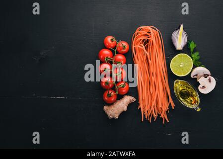 Pasta Rossa Con Pomodori. Cucina Italiana Tradizionale. Su uno sfondo di legno. Vista dall'alto. Spazio di copia. Foto Stock