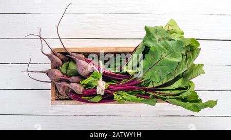 Barbabietole fresche in scatola di legno. Su uno sfondo di legno. Vista dall'alto. Spazio di copia. Foto Stock