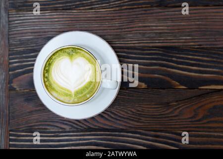 Latte da tè Matcha verde in una tazza bianca su sfondo marrone di legno isolato Foto Stock