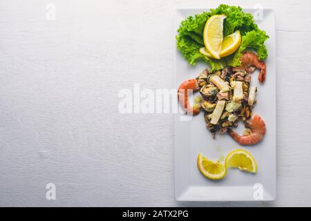 Spuntini freddi. Frutti di mare, gamberetti, cozze, calamari, polpi. Su uno sfondo di legno. Vista dall'alto. Spazio libero. Foto Stock