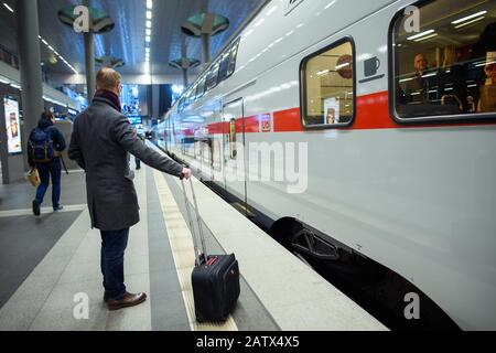 Berlino, Germania. 05th Feb, 2020. Durante la presentazione su un binario nella stazione principale, un passeggero si trova in piedi con una valigia gommata davanti a un treno a due piani dal produttore di veicoli ferroviari Stadler (Stadler KISS) nella livrea interurbana della Deutsche Bahn. I nuovi treni saranno in servizio sulla linea Intercity Rostock-Berlin-Dresden a partire dall' 08.03.2020. Credito: Gregor Fischer/Dpa/Alamy Live News Foto Stock