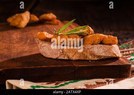 Patatine fritte di maiale fresco sul pane su tavola di legno. Chicharron fatto in casa. Foto Stock