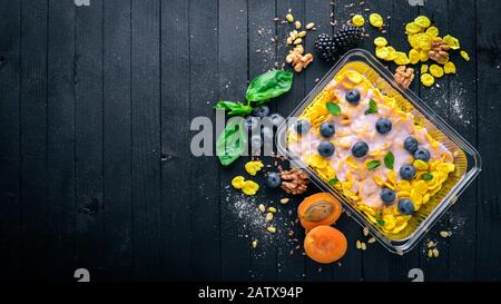 Fiocchi d'avena con mirtilli e yogurt. Cibo dietetico sano. Pranzo boxe. Su uno sfondo di legno nero. Vista dall'alto. Spazio libero per il testo. Foto Stock
