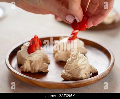Il processo di creazione del dessert di Pavlov, decorando la meringa con fragole Foto Stock