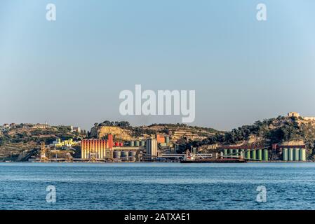 Colorati silos industriali presso il terminal di spedizione vicino alla zona urbana sul fiume Tejo in Portogallo, nel pomeriggio sole Foto Stock