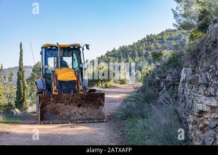 Un caricatore di retroescavatore che lavora su un percorso in una foresta vicino Gerusalemme, Israele Foto Stock