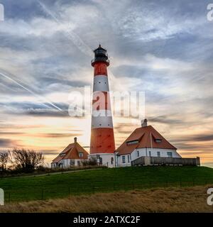Faro Westerhever al tramonto con le nuvole georigie e i colori mozzafiato al Mare del Nord nello Schleswig Holstein, Germania Foto Stock