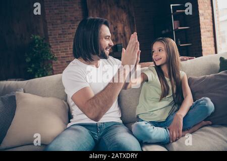 Bravo. Profilo foto di piccola signora divertente eccitato bello daddy sedersi accogliente divano buon umore gioendo squadra di lavoro che batte le braccia ha fatto grande lavoro Foto Stock