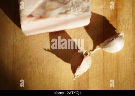 Sul tavolo si trova un pezzo di lardo intero e due spicchi d'aglio Foto Stock