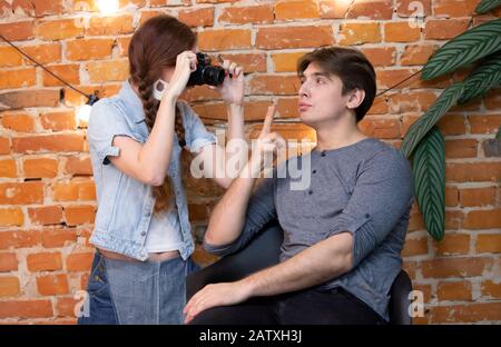 Ragazza fotografo fotografie un ragazzo contro un muro di mattoni Foto Stock