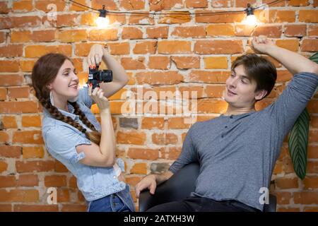 Ragazza fotografo fotografie un ragazzo contro un muro di mattoni Foto Stock