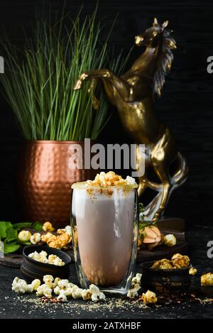 Cacao con latte e popcorn. Nel vetro. Vista dall'alto. Su sfondo nero. Foto Stock