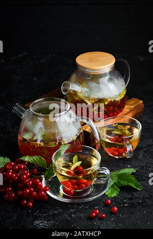 Tè da viburnum e erbe forestali. Bevande calde invernali. Su sfondo nero. Vista dall'alto. Foto Stock