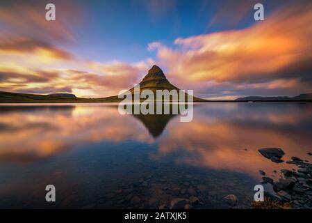 Tramonto sul monte Kirkjufell con riflessione in un vicino lago in Islanda Foto Stock