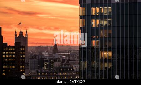 Tramonto A Londra. Una vista sulla capitale del Regno Unito con la bandiera sormontata dalla Torre Victoria, il Palazzo di Westminster, che contrasta con lo skyline. Foto Stock