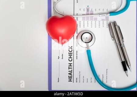 Assistenza sanitaria e concetto mediacale. Vista dall'alto dello stetoscopio e del cuore rosso sulla tabella di salute. Foto Stock